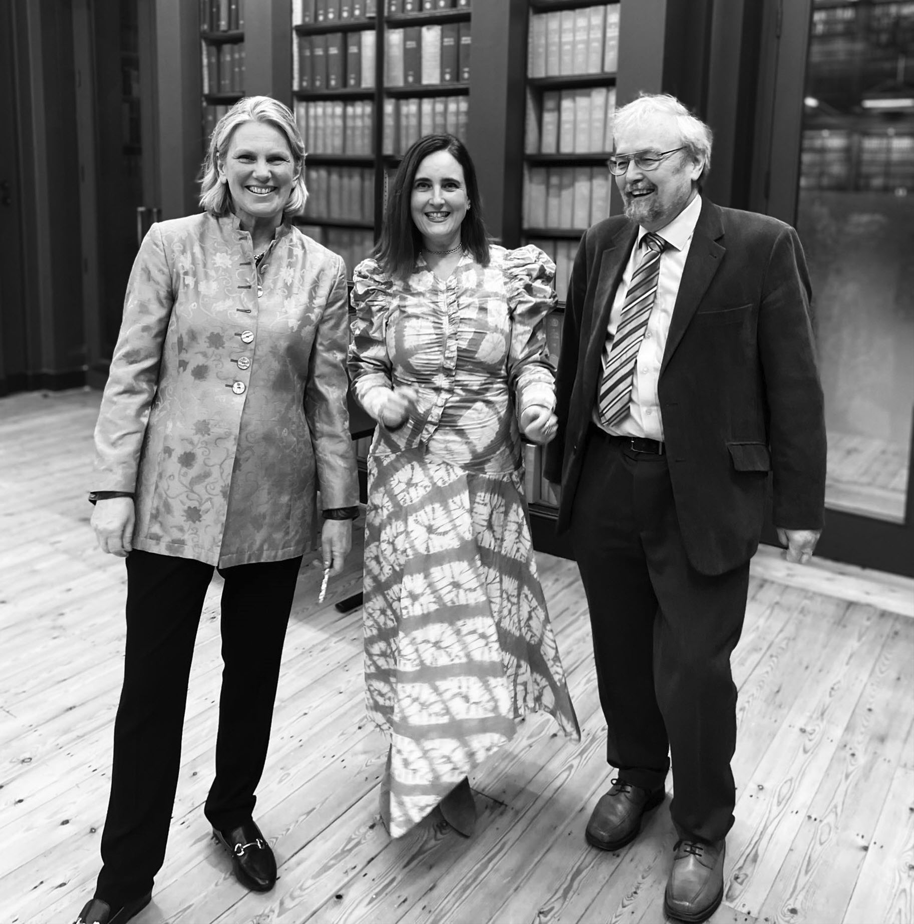 Authors Camilleri, Rockey and Dunbar who wrote The Social Brain. Two females and a male standing in a library, smartly dressed, black and white photo.