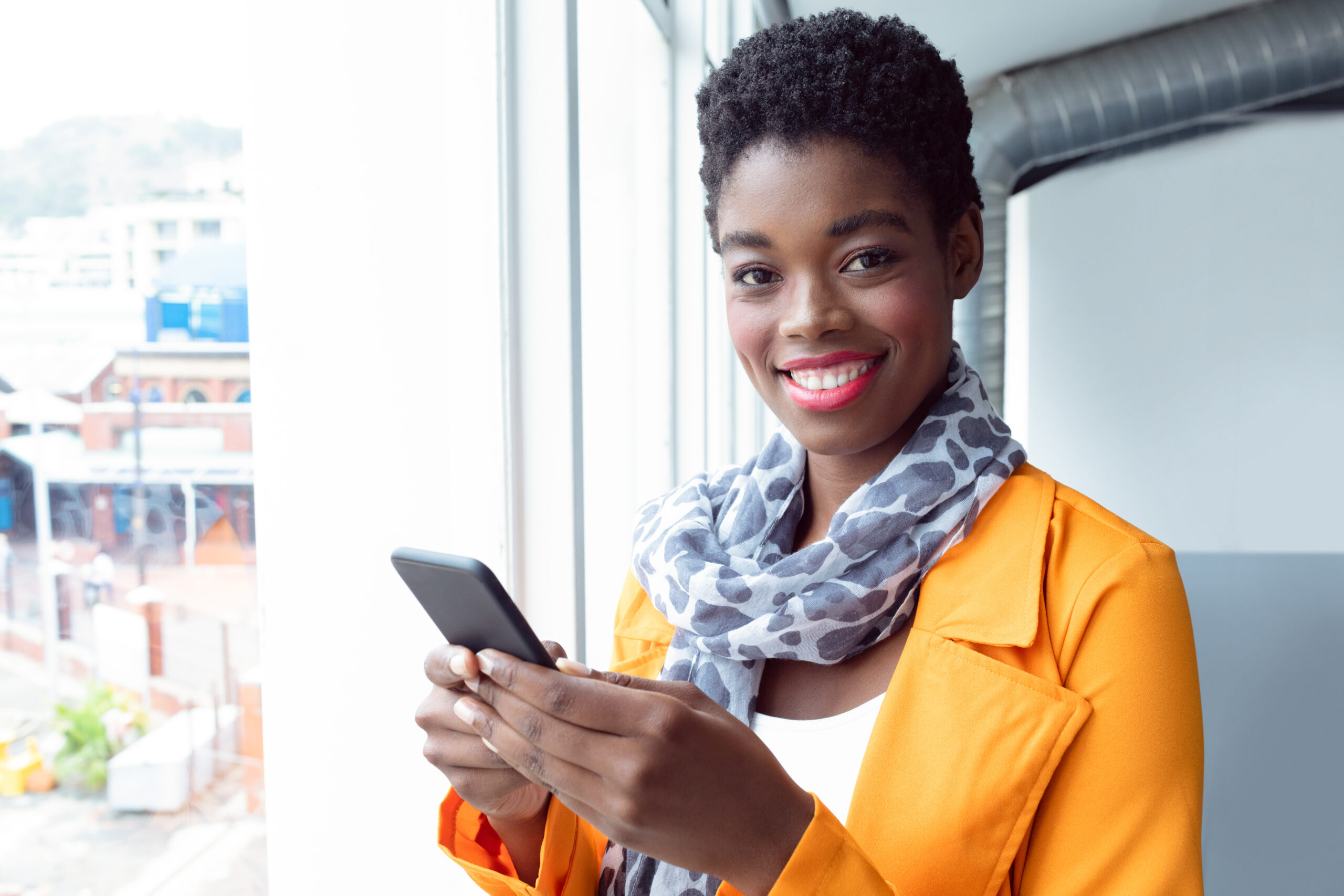 Businesswoman using mobile phone near window in office