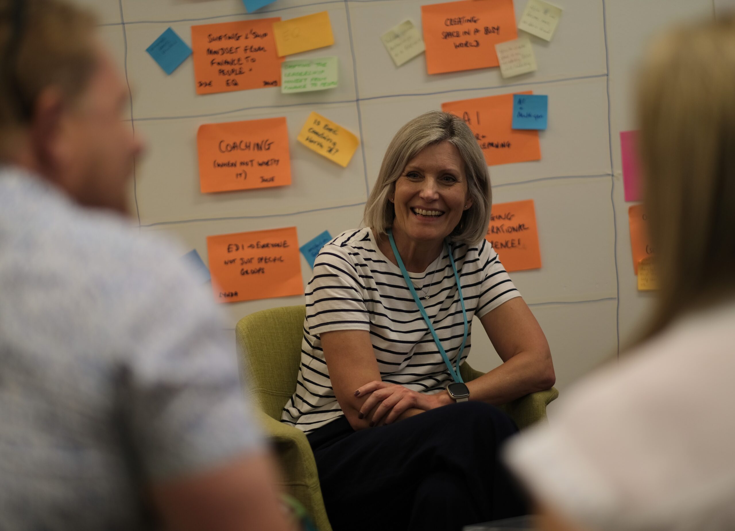 Woman smiling with a wall of post-it notes behind her