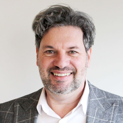 Ger Driesen - white male with grey hair, wearing a suit, smiling.