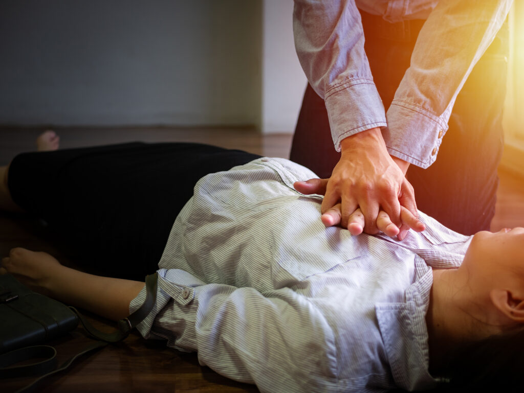 volunteer office man use hand pump on chest for first aid emergency CPR on heart attack woman unconscious, try to resuscitation patient woman at work