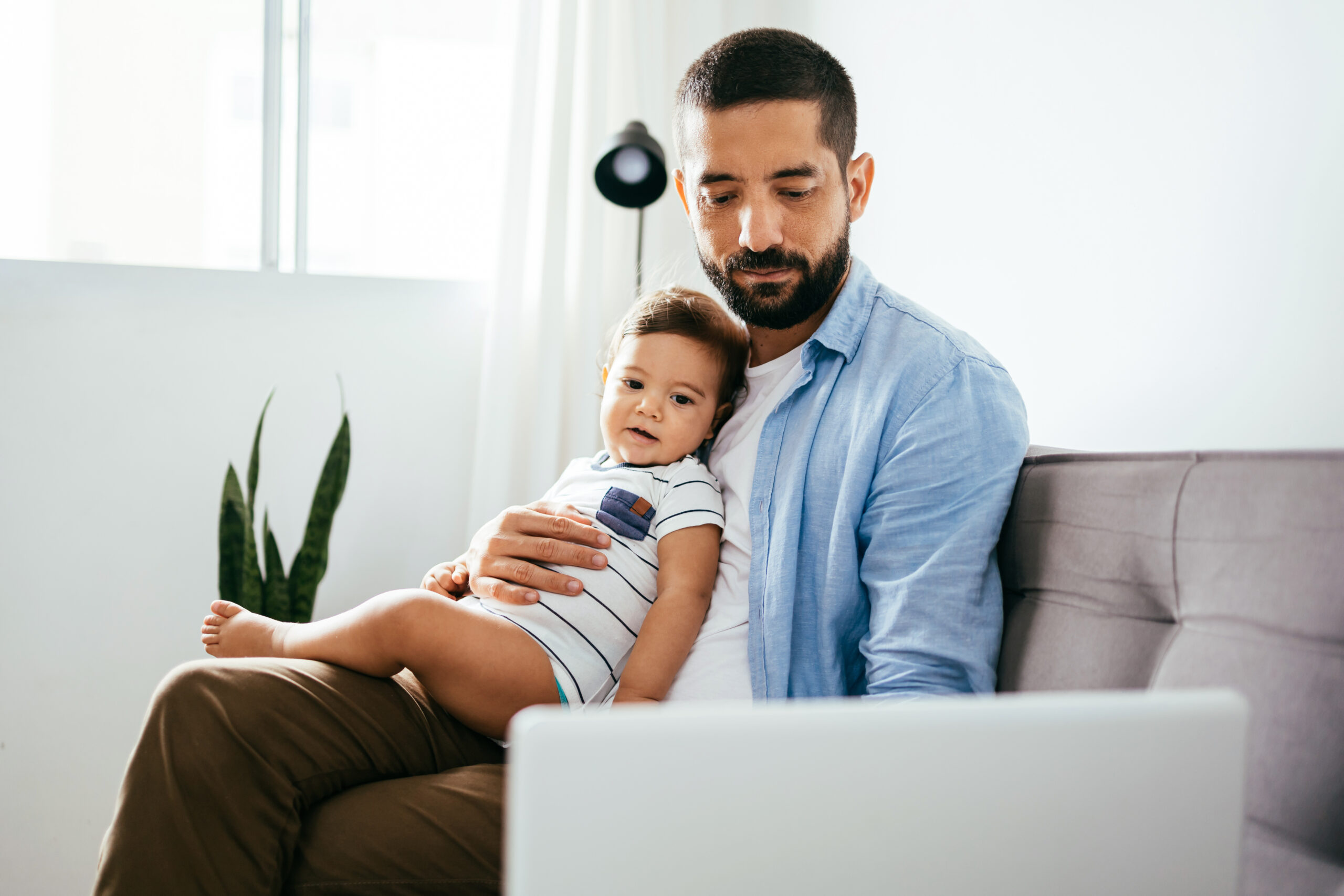 Father working with his baby boy in home office with laptop. Work from home concept