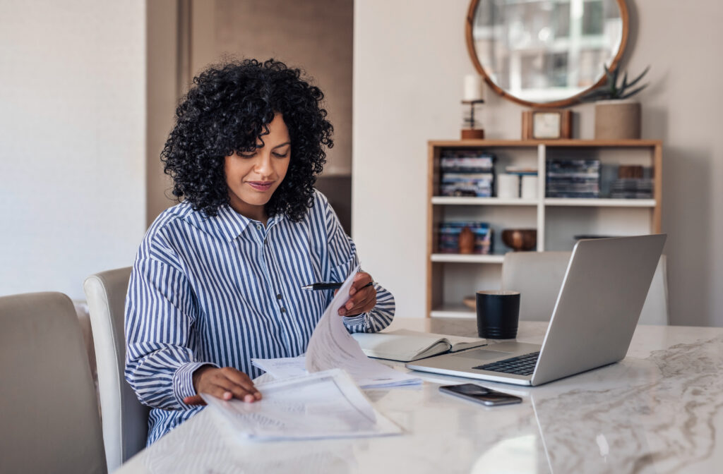 Smiling female entrepreneur going through paperwork at her dining table