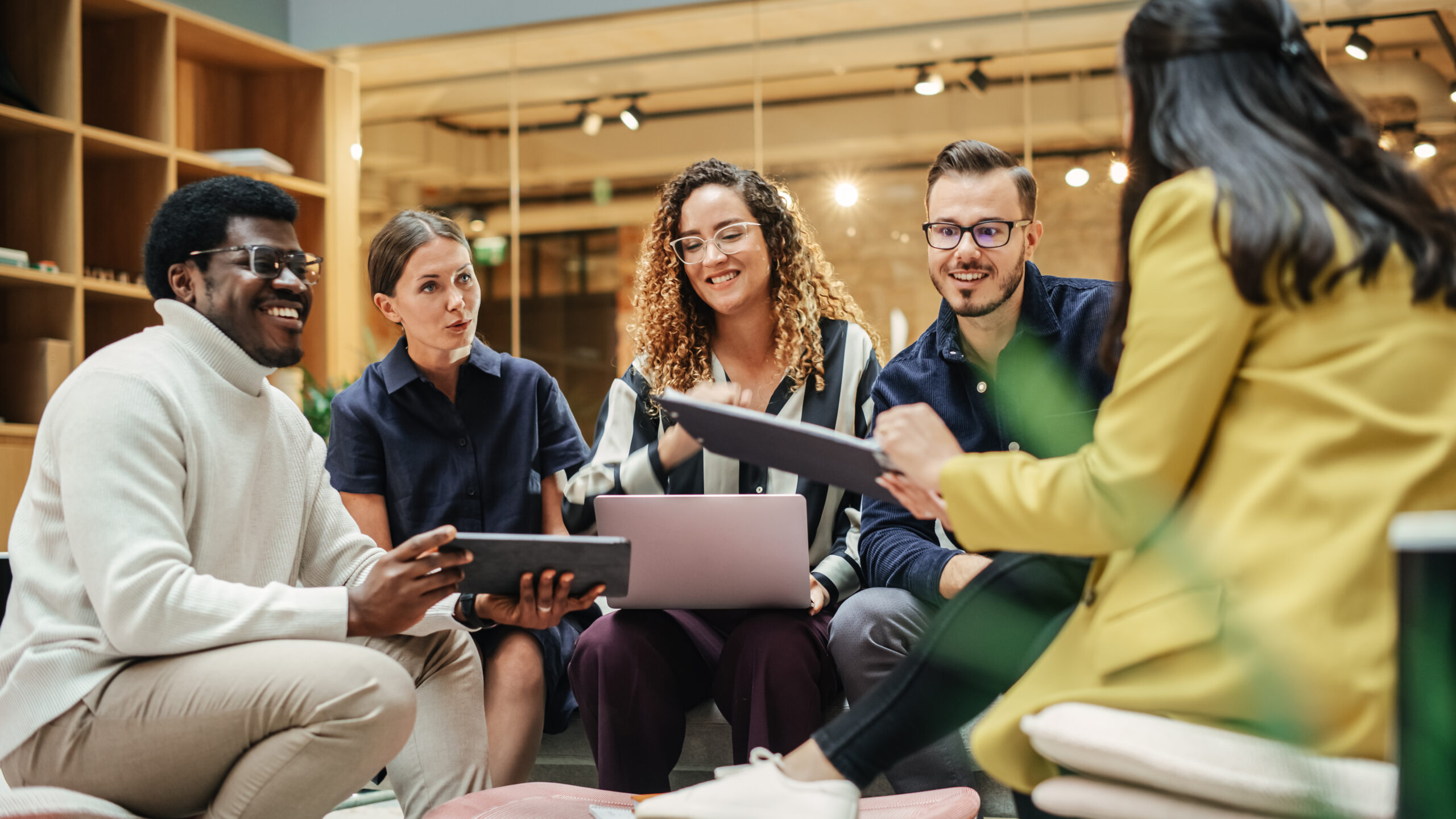 Multiethnic Group of People Meeting and Discussing Innovative Ideas in a Casual Conference Room in the Office. Smiling Colleagues Putting Together a Presentation