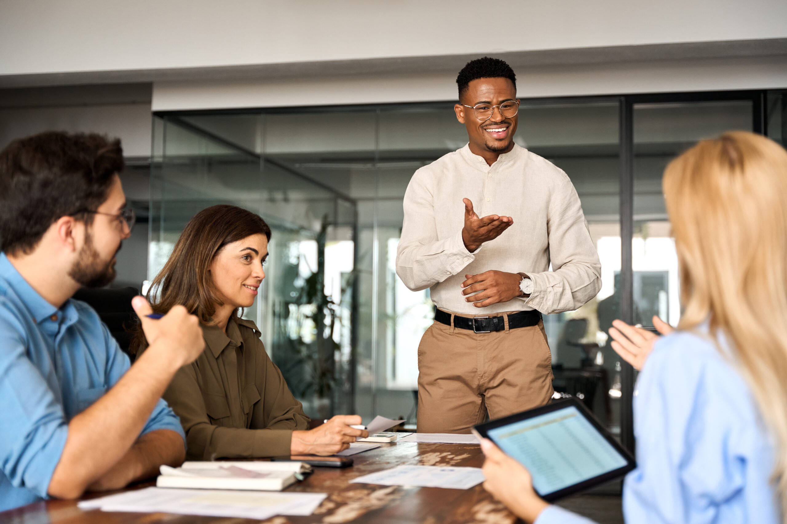 Young happy African American male executive company leader discussing project management planning strategy working with diverse busy colleagues company team at office corporate board group meeting.