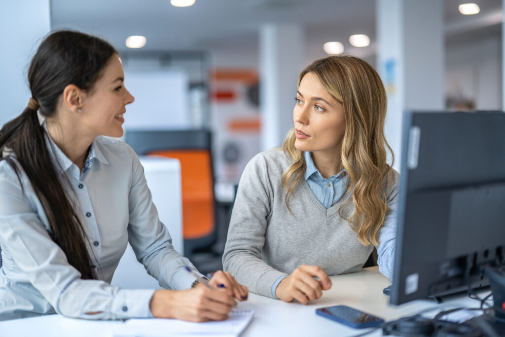 Two beautiful business women working together on computer in the office